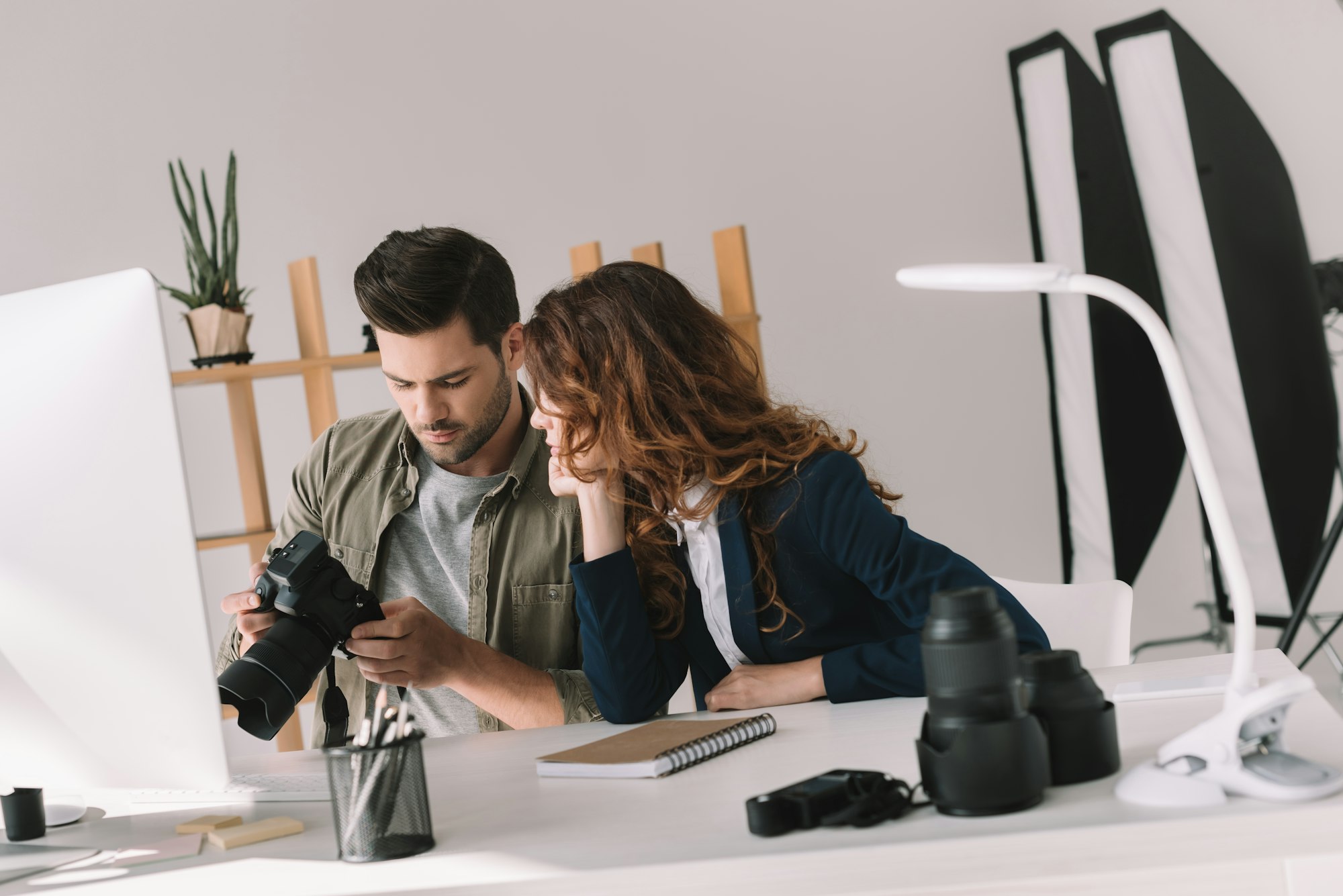 male photographer and model choosing photos for portfolio in modern office