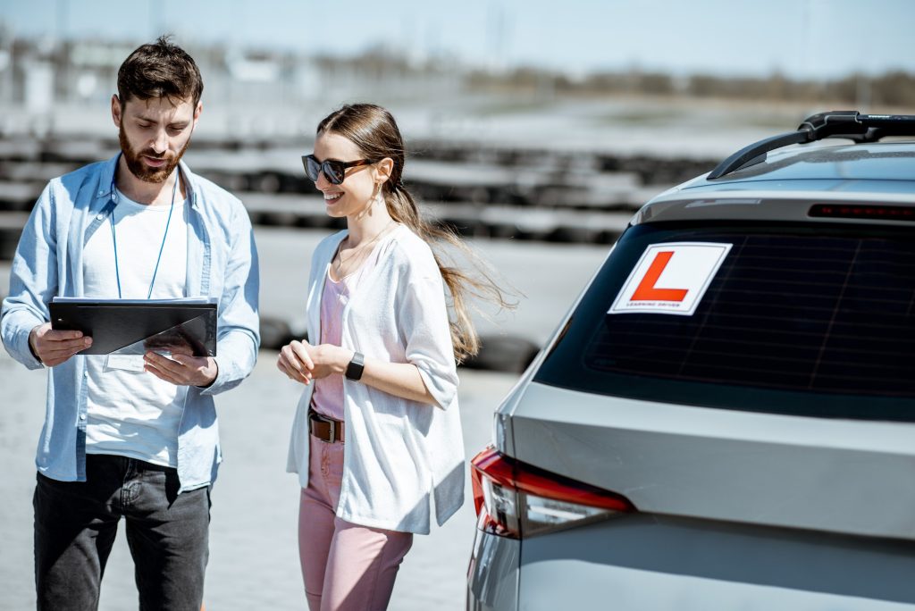 Instructor with female student at the driving school outdooors