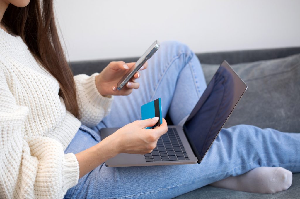 Online payment, a woman holds a smartphone and uses a credit card for online purchases.