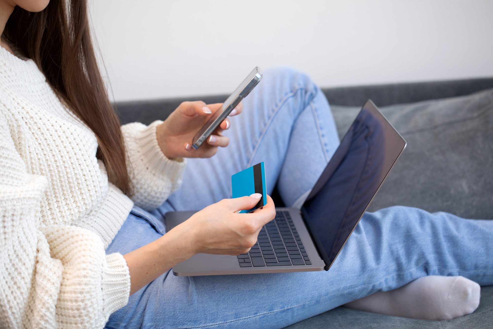 Online payment, a woman holds a smartphone and uses a credit card for online purchases.