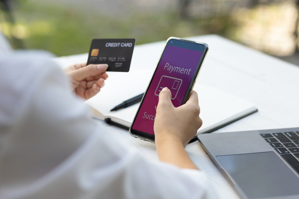 Woman holding credit card and using smart phone. Online payment and online shopping concept.