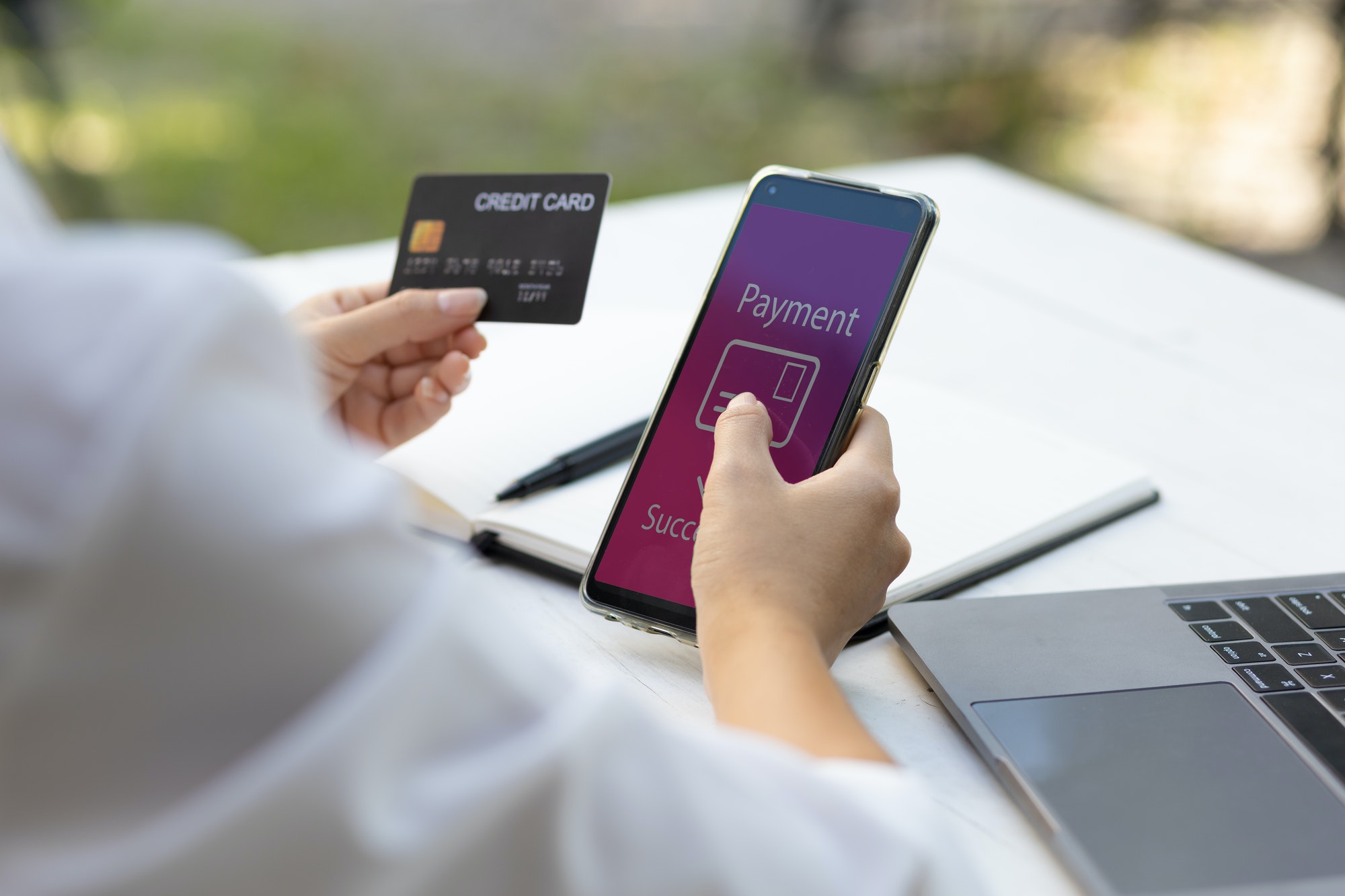 Woman holding credit card and using smart phone. Online payment and online shopping concept.