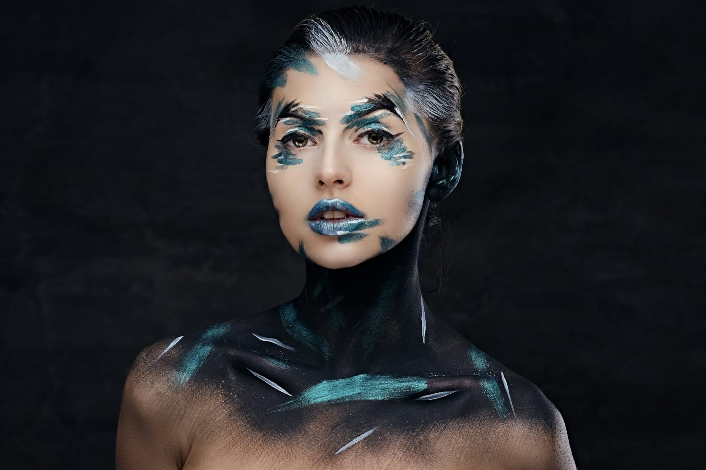 A woman with colorful make up and painted art on a neck.