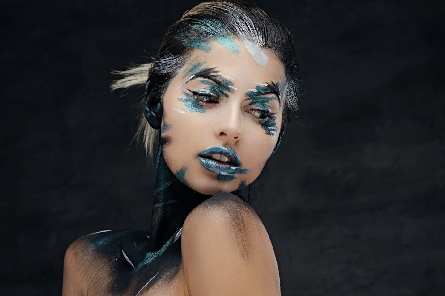 A woman with colorful make up and painted art on a neck.
