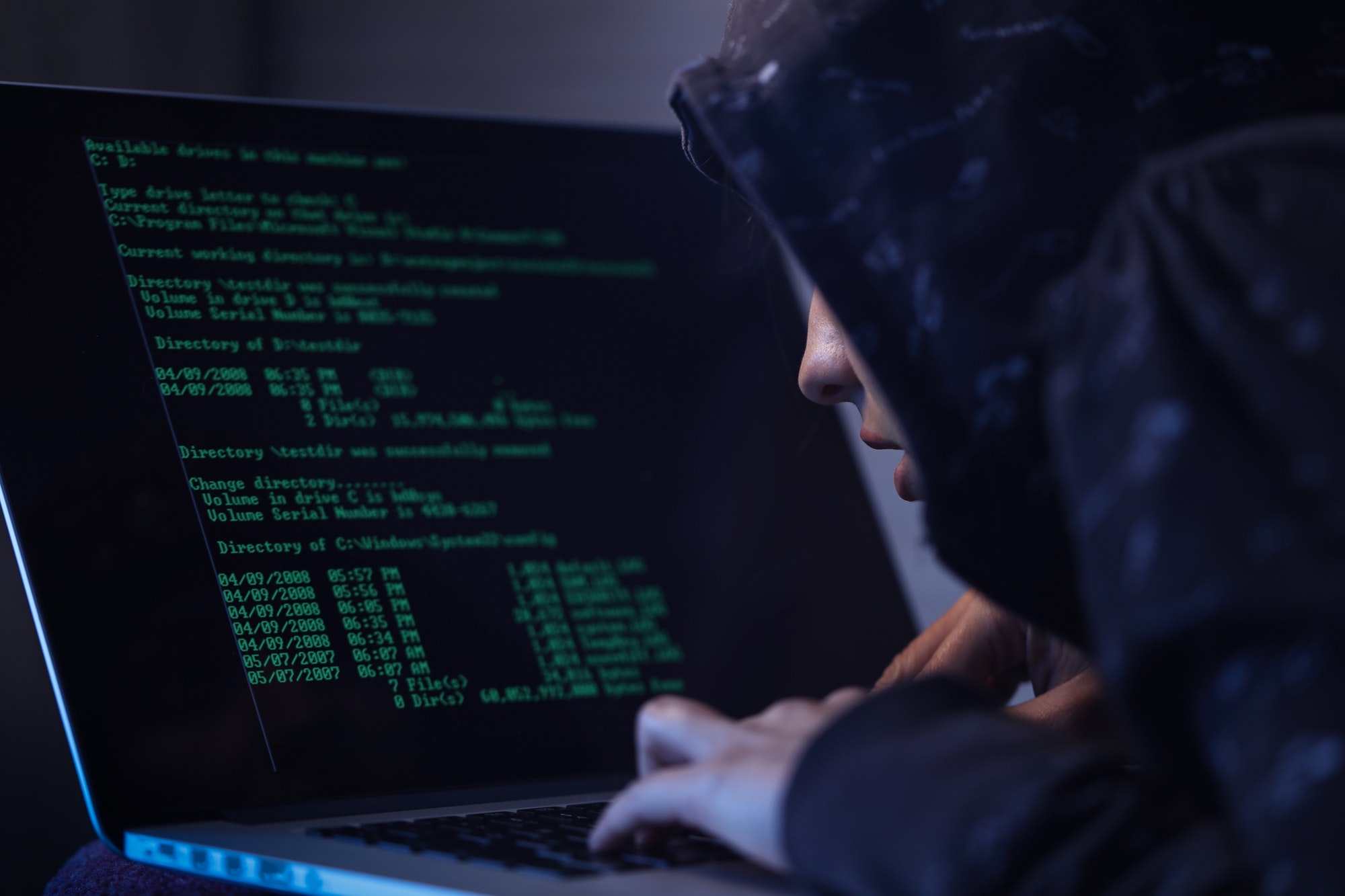 Computer hacker programming software while stealing data on laptop.
